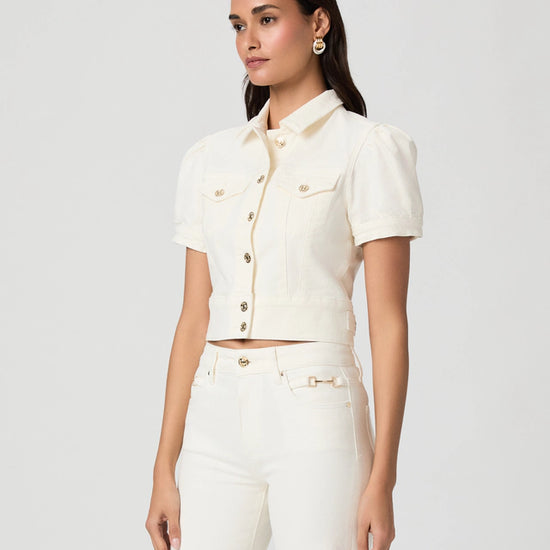 Woman wearing a white denim jacket and pants on a plain background