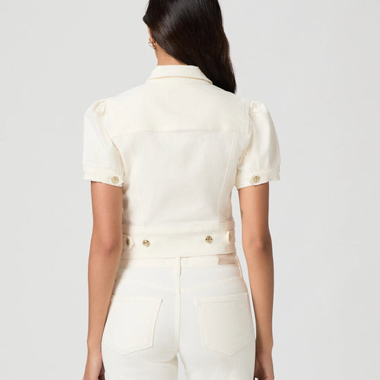 Woman wearing a white outfit with gold buttons on a light gray background