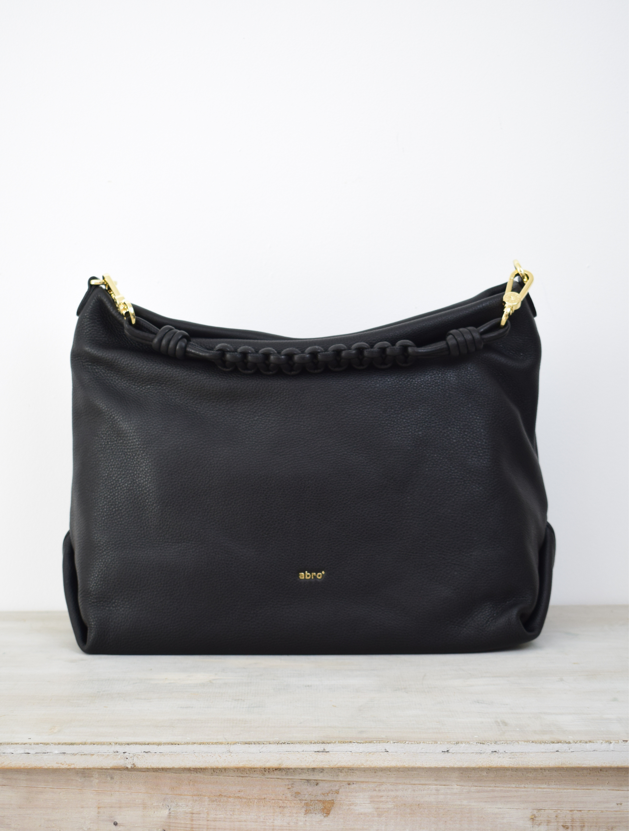Italian black leather bag with a woven shoulder strap and cross body strap with gold toned hardwear