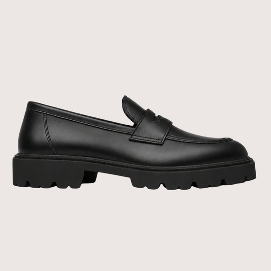 black leather penny loafer with black sole on a light background product shot 