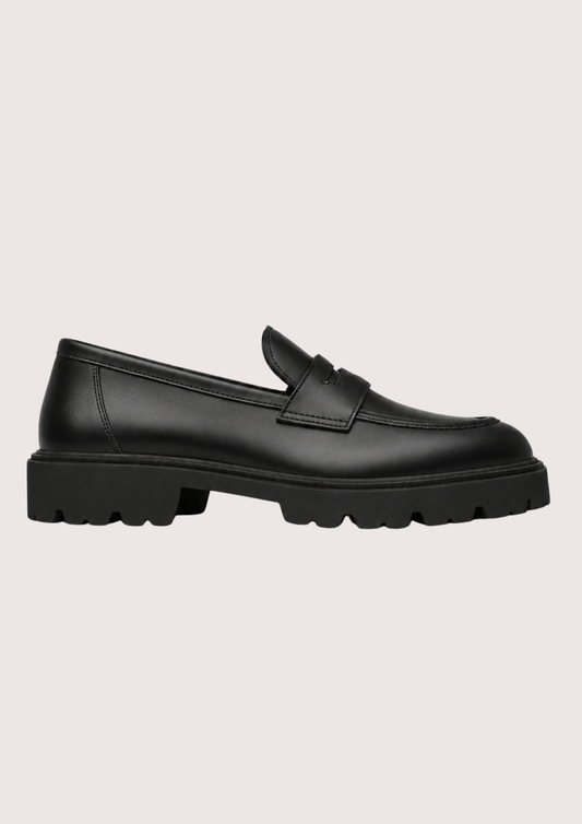 black leather penny loafer with black sole on a light background product shot 