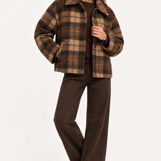 A woman modeling a brown and tan plaid cropped jacket with a wide collar, paired with dark brown wide-leg pants and dark brown boots, against a plain white studio background.