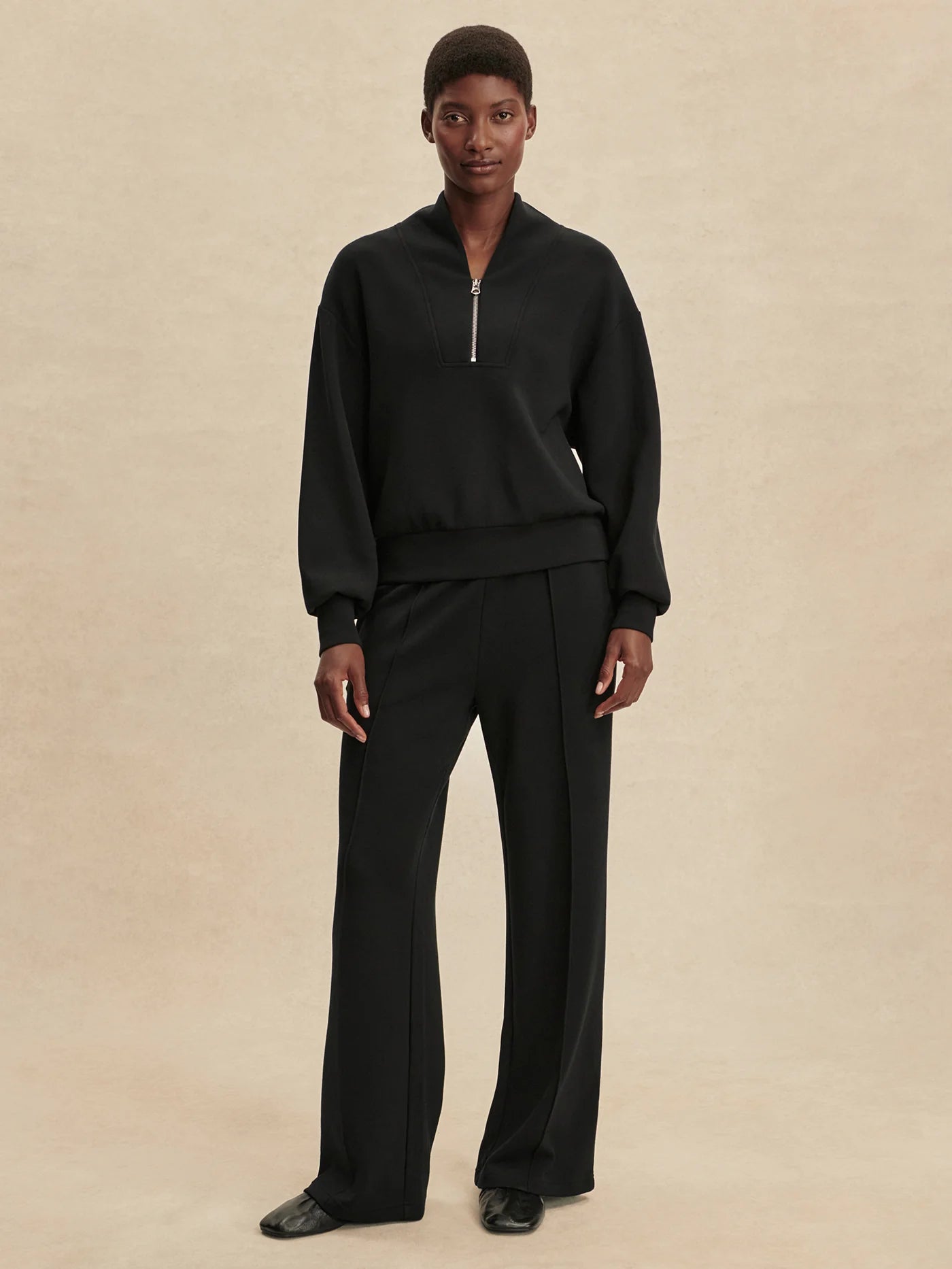 Quarter zip and slightly cropped black sweat top with shawl collar and V neckline from varley model shot
