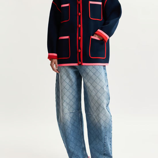 model wearing baggy jeans and a colourful jumper on a plain background 
