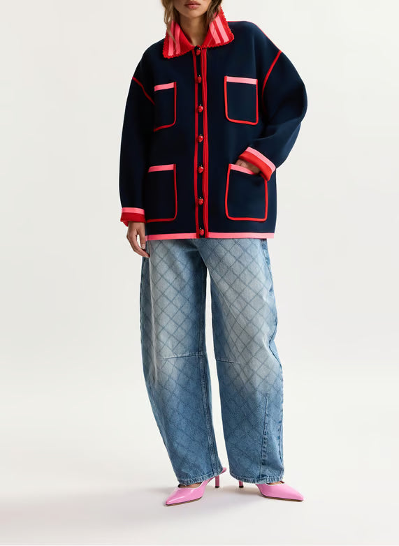 model wearing baggy jeans and a colourful jumper on a plain background 