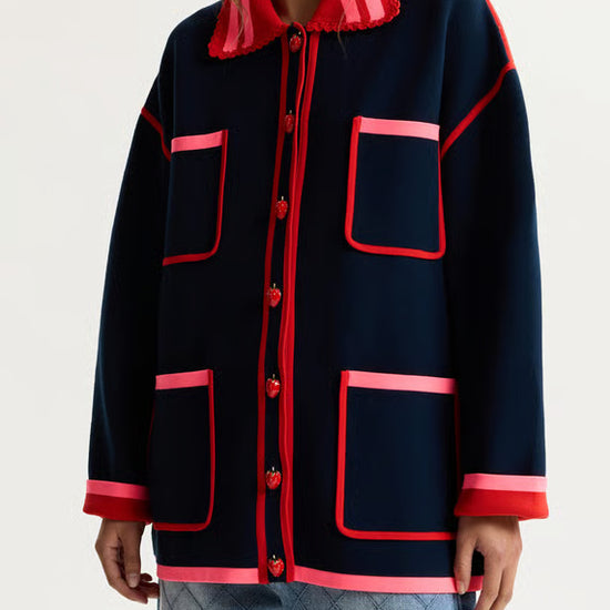 Navy jacket with red accents worn by a person on a light gray background