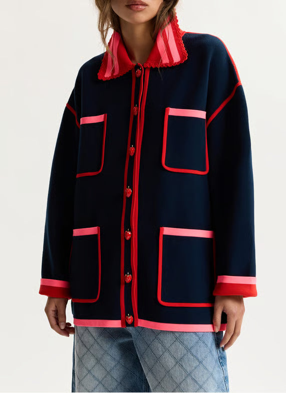 Navy jacket with red accents worn by a person on a light gray background