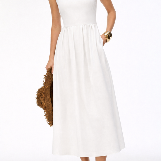 Woman wearing a white sleeveless dress holding a brown jacket on a white background