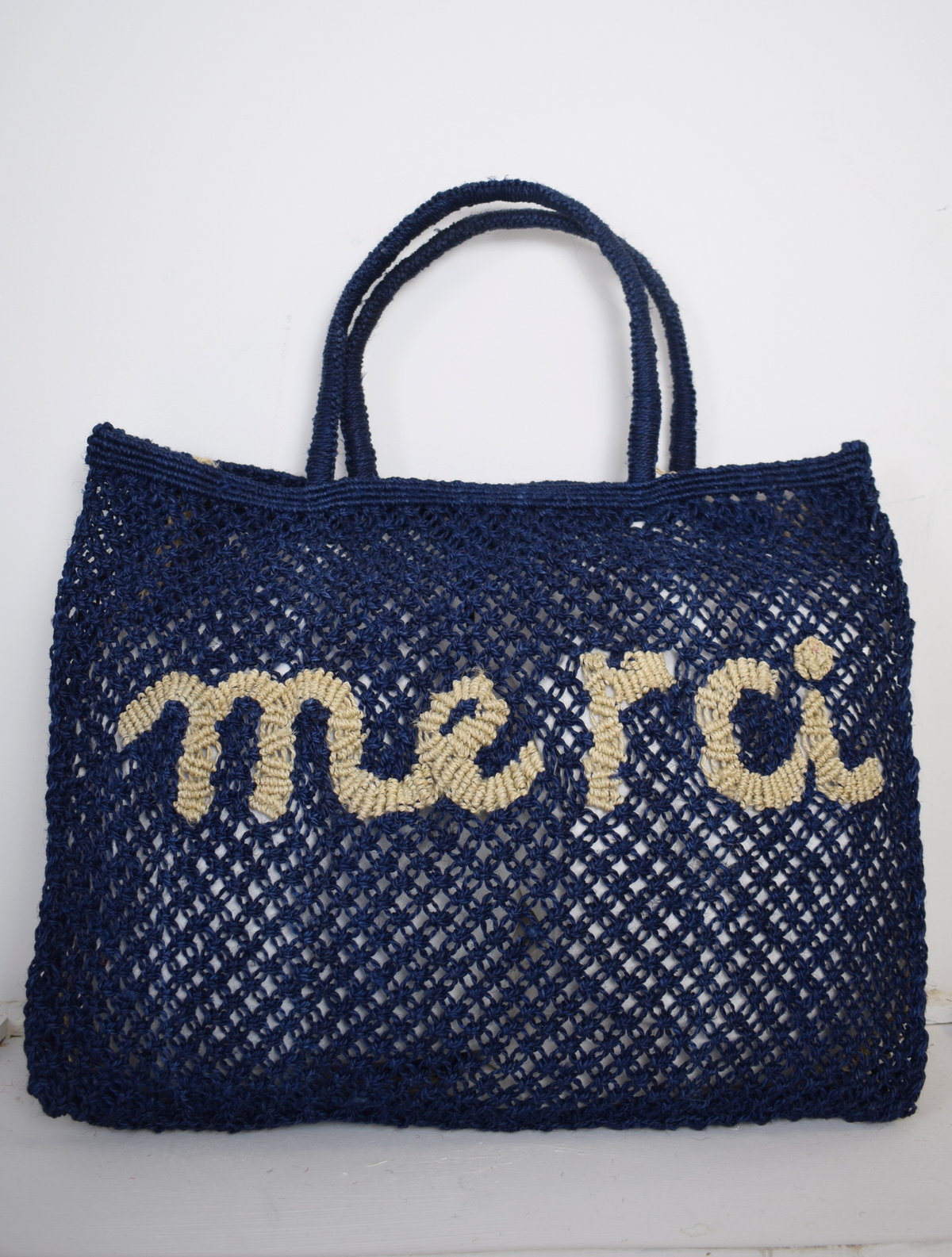 Blue woven bag with neautral writing on saying Merci 