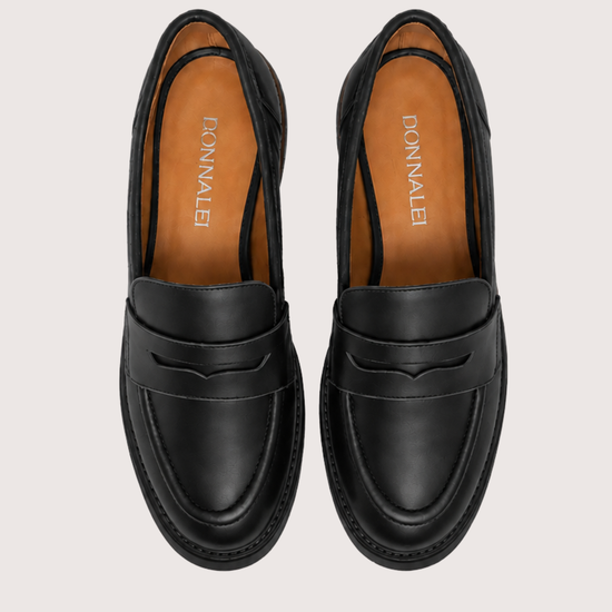 A pair of black leather penny loafers shown from a top-down view on a light beige background. The insoles are tan with the brand name 'DONNALEI' printed vertically in white.