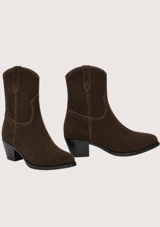 A pair of dark brown suede western-style ankle boots with low block heels, shown from the side and back-three-quarter angles against a solid light beige background.