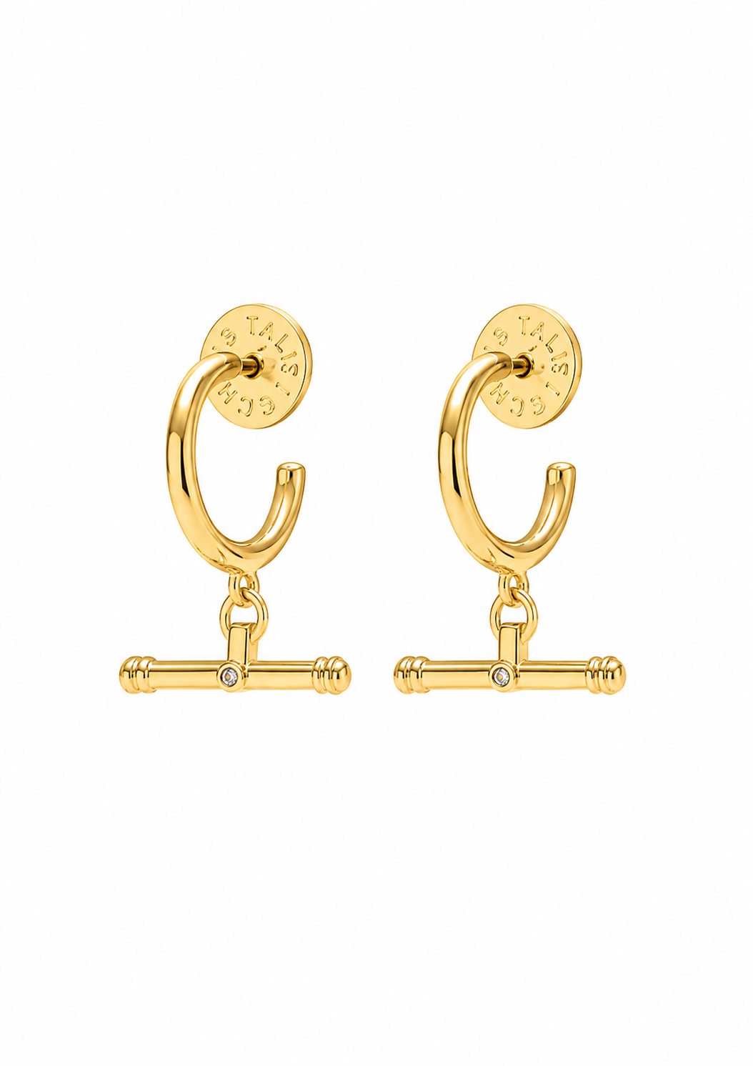 A pair of gold huggie hoop earrings with a dangling barbell charm and a small clear rhinestone in the center, shown on a plain white background.