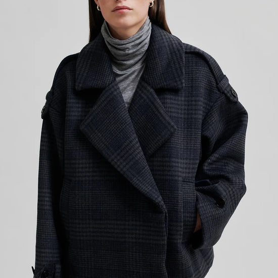 dark grey check jacket with wide collar and straps on cuffs and shoulders model shot