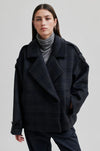 dark grey check jacket with wide collar and straps on cuffs and shoulders model shot