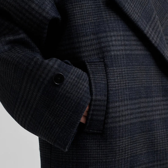 dark grey check jacket with wide collar and straps on cuffs and shoulders close up