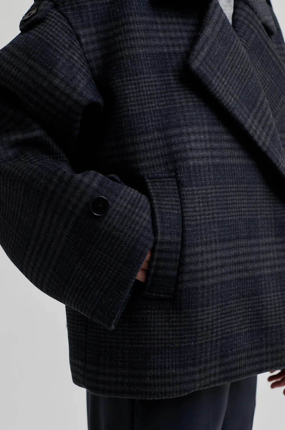 dark grey check jacket with wide collar and straps on cuffs and shoulders close up