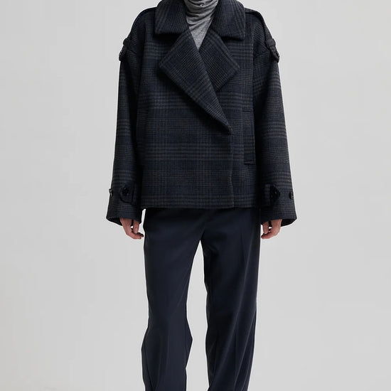 dark grey check jacket with wide collar and straps on cuffs and shoulders model shot