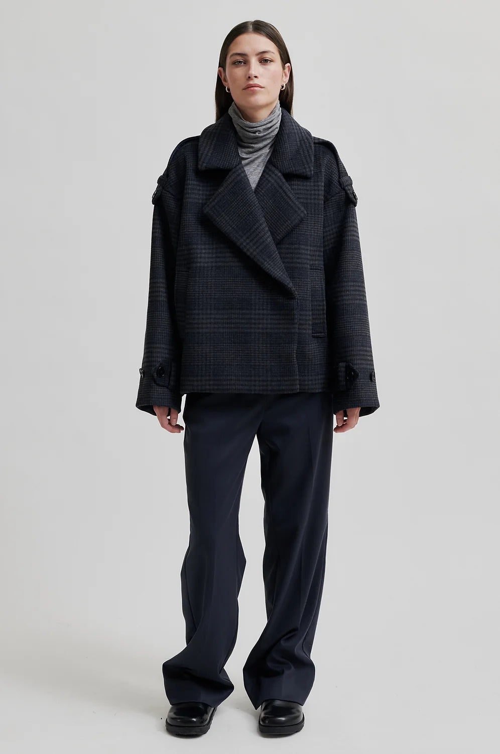 dark grey check jacket with wide collar and straps on cuffs and shoulders model shot