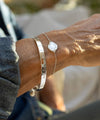 Close-up of a person's wrist wearing two bracelets with engraved text, blurred background