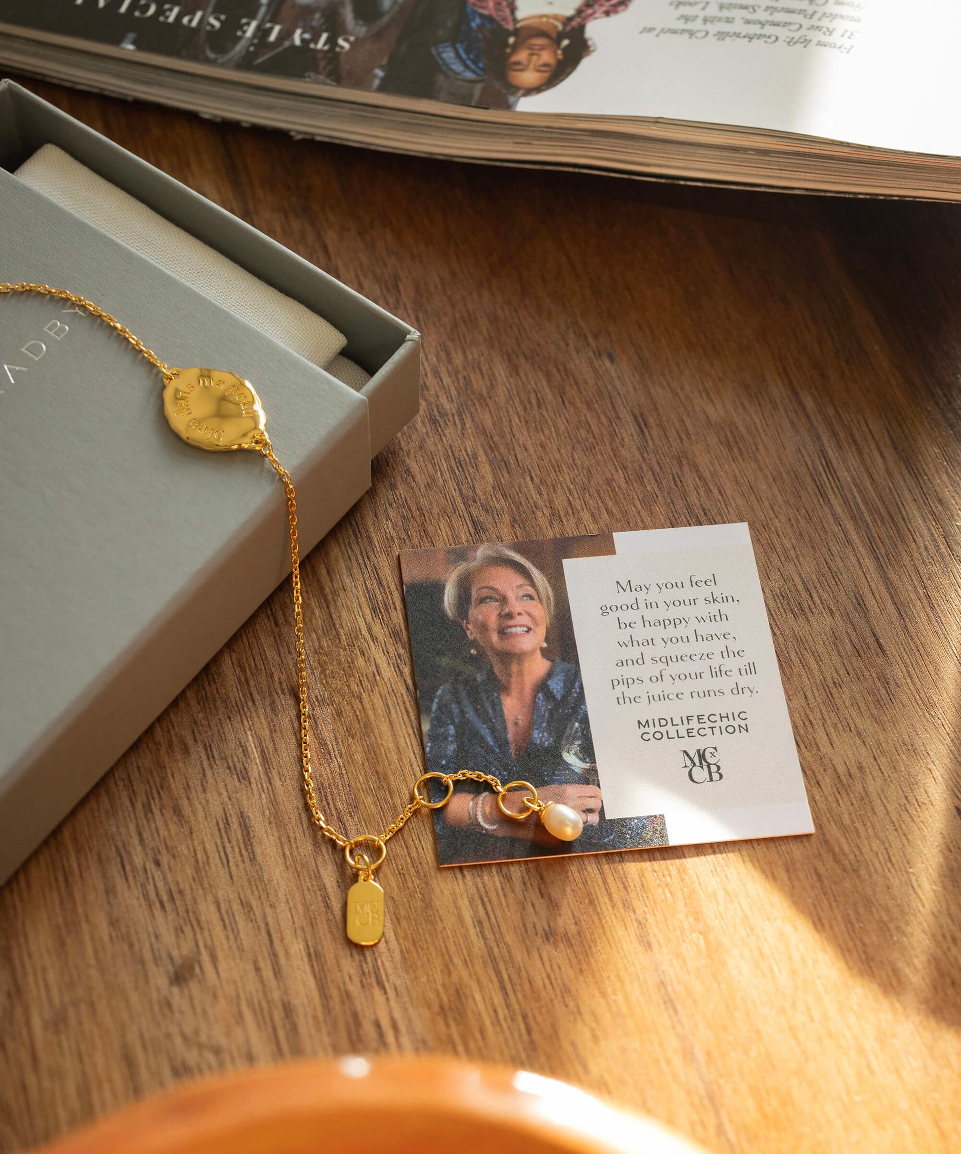 Gold necklace with a pendant on a card featuring a woman's face, placed on a wooden surface.