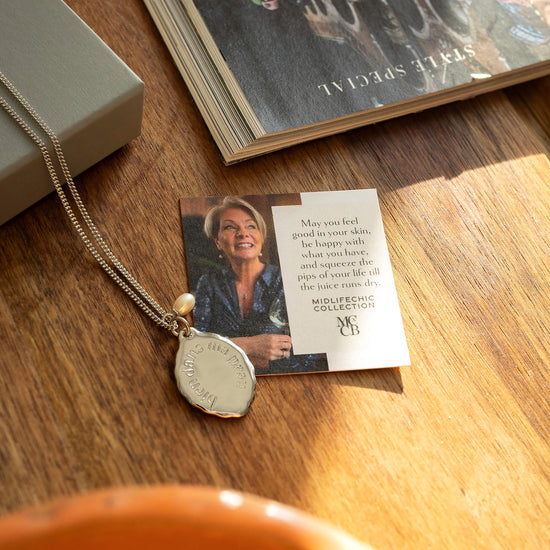 Necklace with pendant and card on a wooden surface
