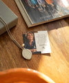 Necklace with pendant and card on a wooden surface