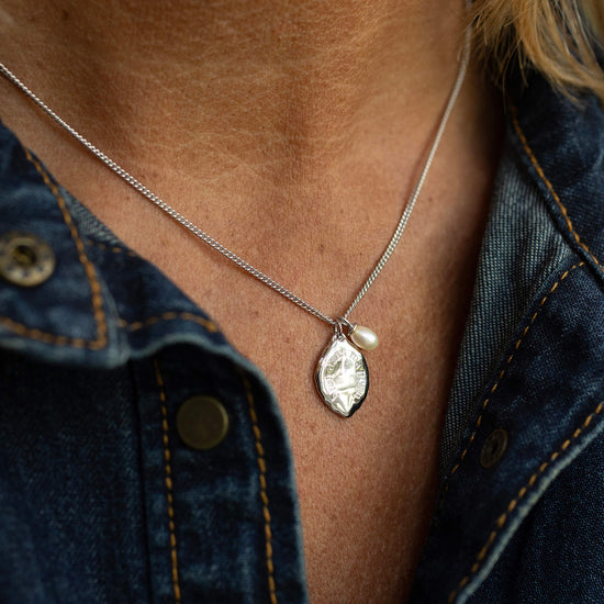 Necklace with a pendant worn by a person against a denim background