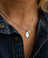 Necklace with a pendant worn by a person against a denim background