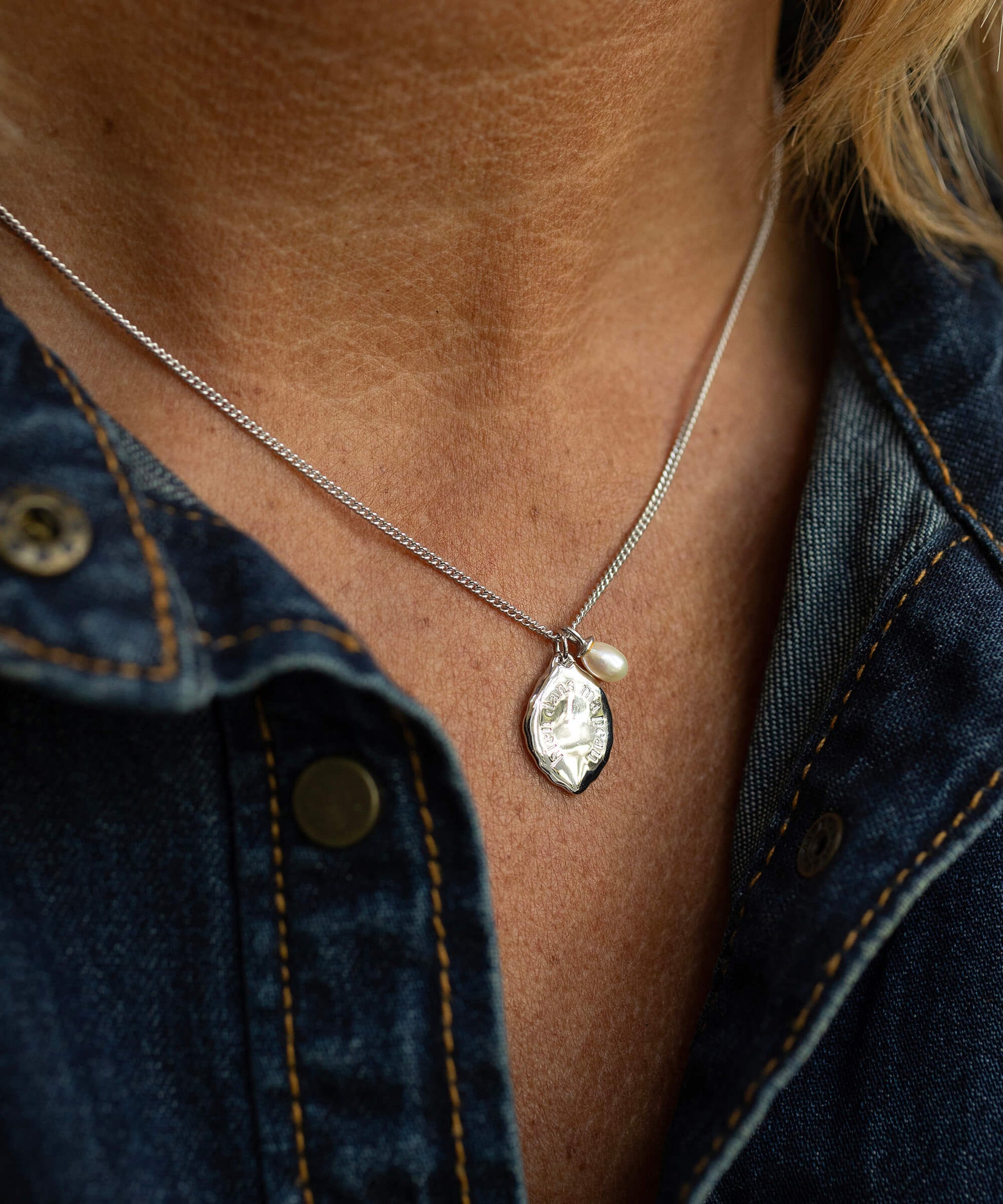 Necklace with a pendant worn by a person against a denim background