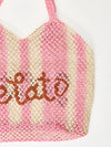 pink and white straw bag with slogan on white background zoomed in