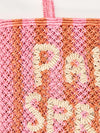 pink and orange string bag with slogan on a white background zoomed in
