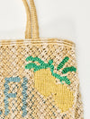 yellow and beige string bag with slogan on white background zoomed in 
