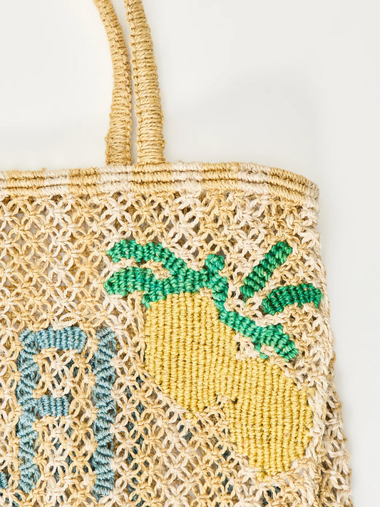 yellow and beige string bag with slogan on white background zoomed in 