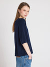 Woman wearing a navy blue sweater and jeans on a light gray background