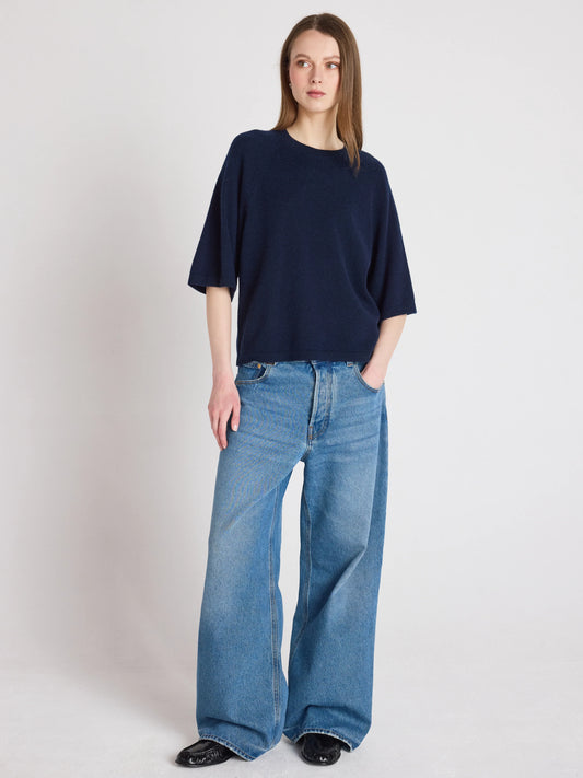 Person wearing a navy sweater and blue jeans on a white background
