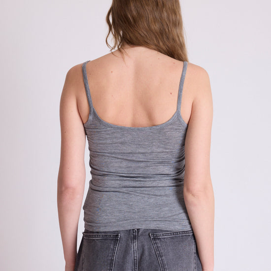 A woman shown from the back wearing a heather gray ribbed tank top and dark gray jeans against a plain light gray studio background.