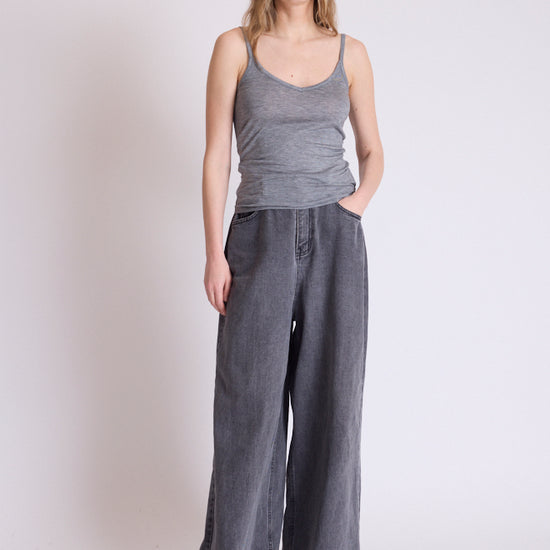 A woman modeling a gray ribbed tank top and wide-leg gray pants against a plain light gray studio background.