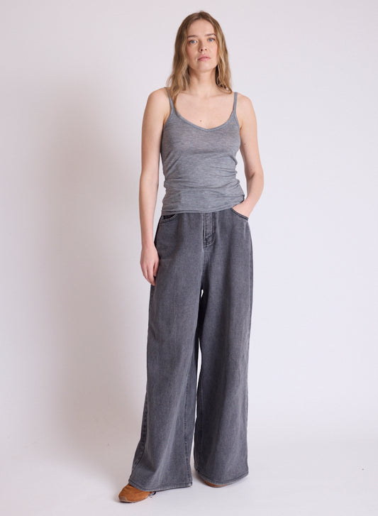 A woman modeling a gray ribbed tank top and wide-leg gray pants against a plain light gray studio background.