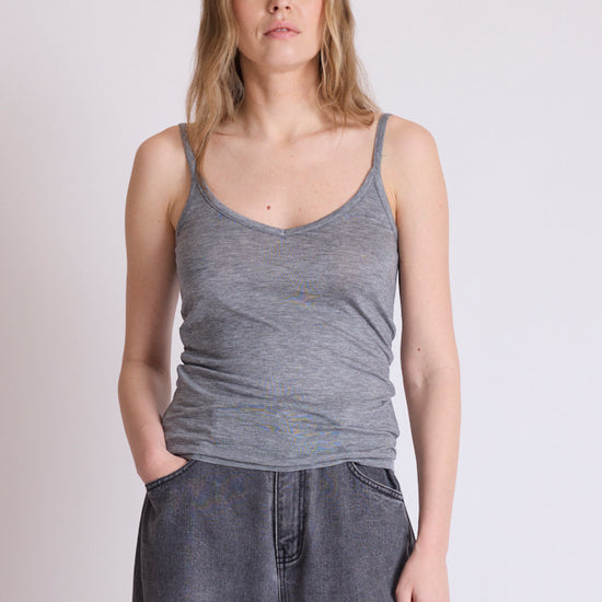 A woman modeling a heather gray ribbed tank top with wide-leg gray denim pants, standing against a plain light gray studio background.