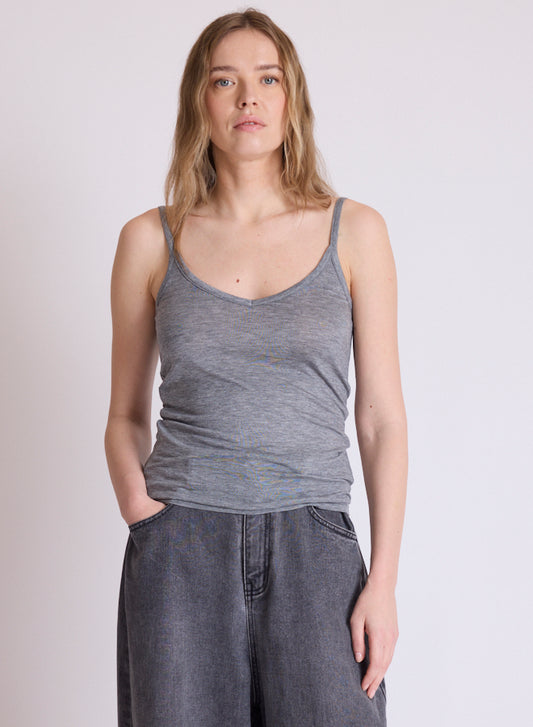A woman modeling a heather gray ribbed tank top with wide-leg gray denim pants, standing against a plain light gray studio background.