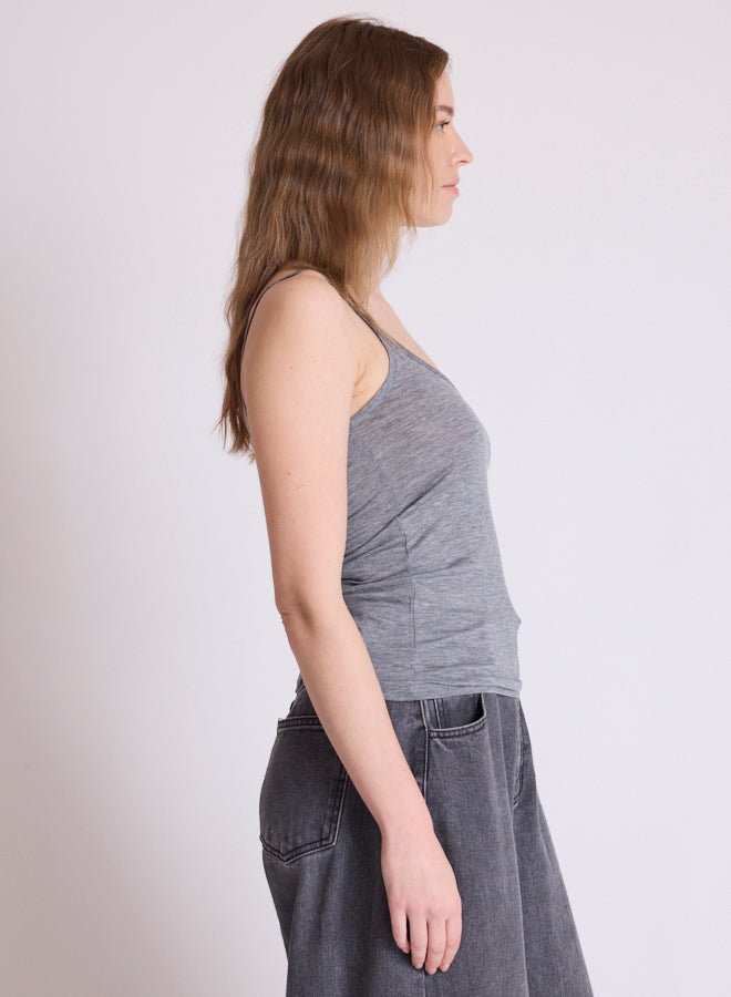 A woman shown in side profile wearing a heather gray ribbed tank top and dark gray denim skirt against a plain light gray studio background.