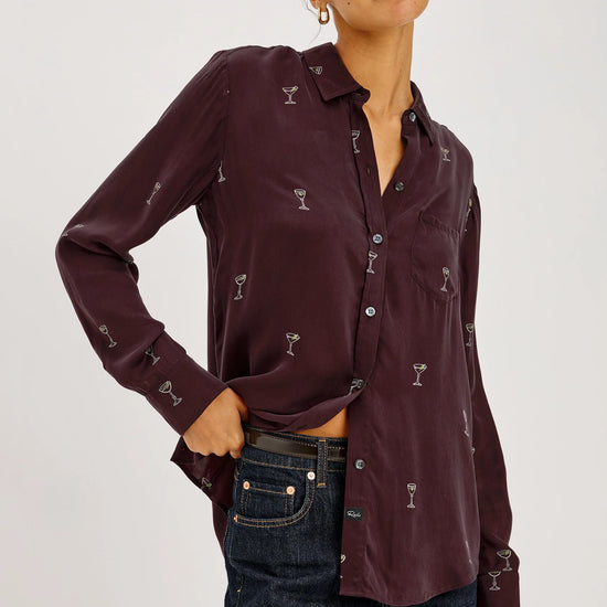 a model wearing A long-sleeve button-up shirt in deep burgundy with a repeating small white cocktail glass pattern,