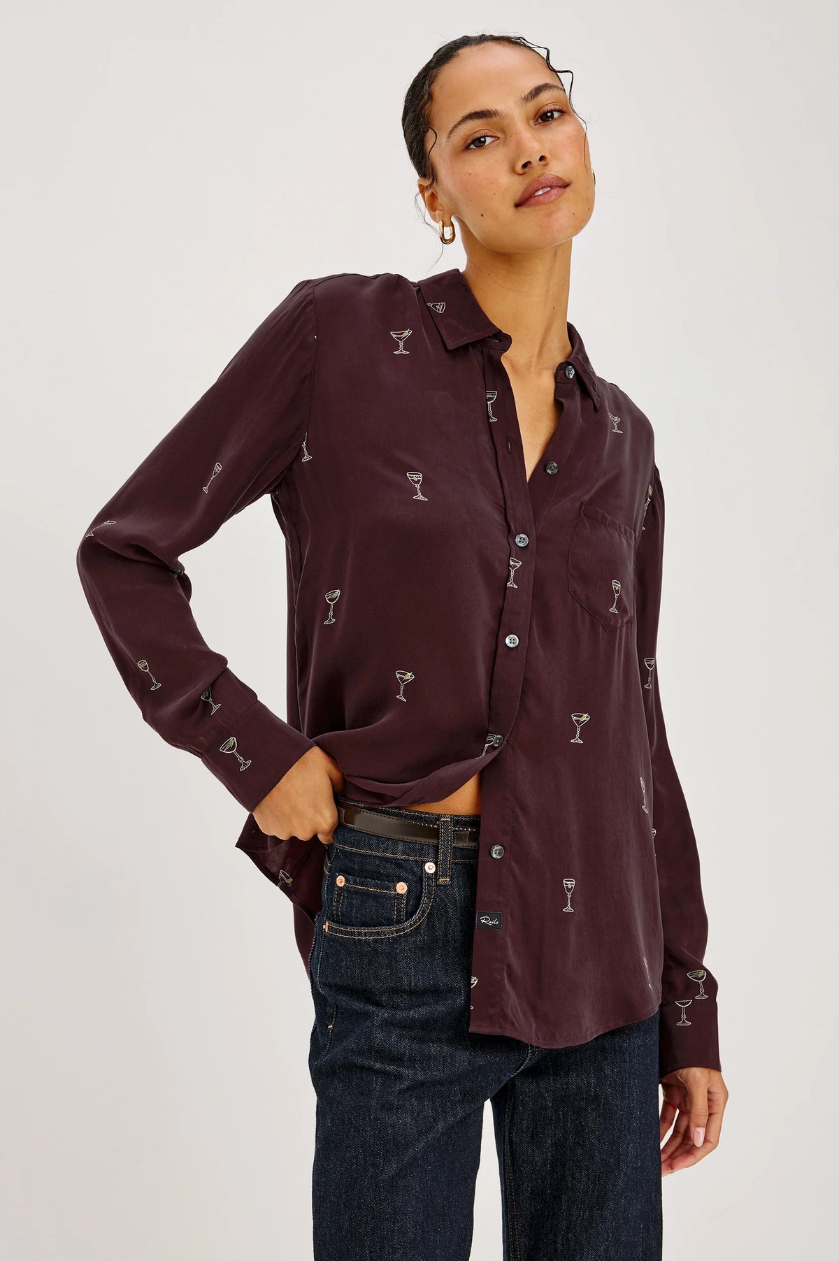 a model wearing A long-sleeve button-up shirt in deep burgundy with a repeating small white cocktail glass pattern,