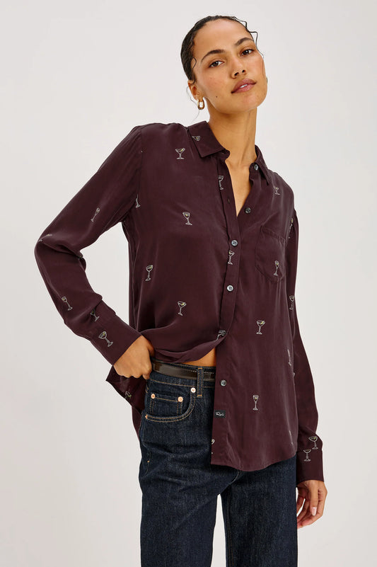 a model wearing A long-sleeve button-up shirt in deep burgundy with a repeating small white cocktail glass pattern,