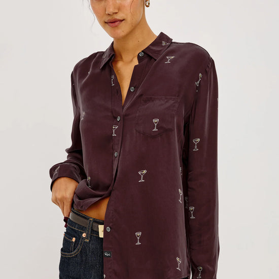 a model wearing A long-sleeve button-up shirt in deep burgundy with a repeating small white cocktail glass pattern,