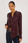 a model wearing A long-sleeve button-up shirt in deep burgundy with a repeating small white cocktail glass pattern,