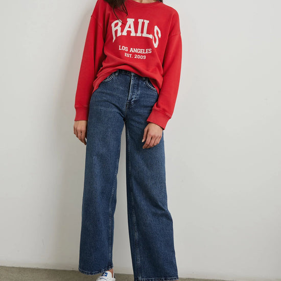 Red sweatshirt with blue jeans on model