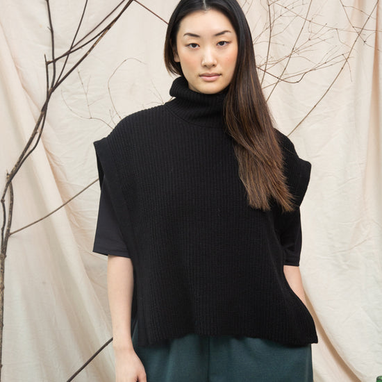 black knitted vest with rib detailing, sleeveless and roll neck model shot