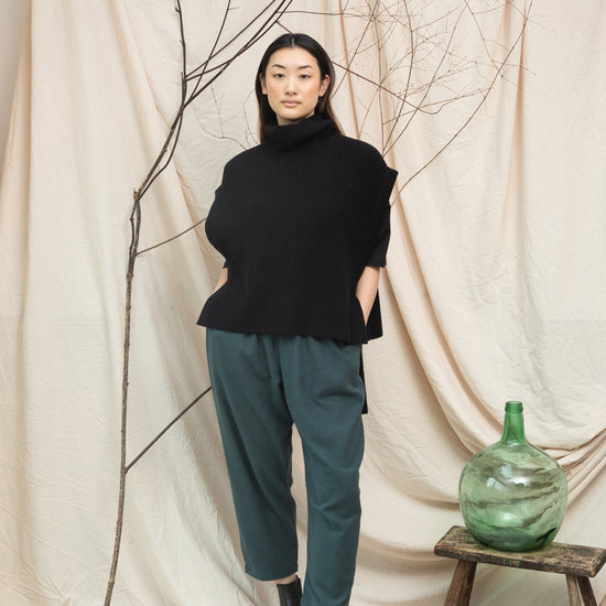 black knitted vest with rib detailing, sleeveless and roll neck model shot