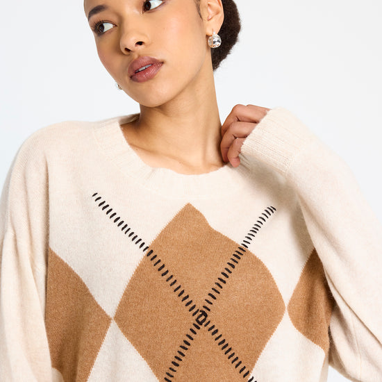 cream round neck cashmere jumper with rib detailing and tan argyle design on the front model shot